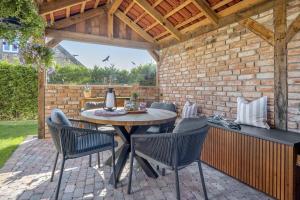 a patio with a table and chairs and a brick wall at Exklusives Ferienhaus Samyel in Warendorf