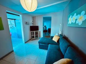 Sala de estar azul con sofá y TV en Ti Caz de Ness, en Saint-Leu