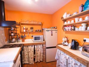 una cucina con pareti arancioni e frigorifero bianco di Rye Court Cottage a Birtsmorton
