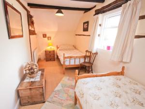 una camera da letto con due letti, un tavolo e una finestra di Rye Court Cottage a Birtsmorton