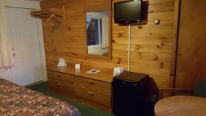 a bedroom with a dresser with a television on a wall at Clark's Beach Motel in Old Forge