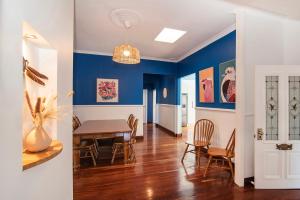 a dining room with blue walls and a table and chairs at Seashells Beach house on Dorset in Busselton