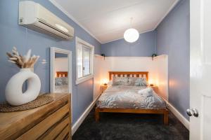 a bedroom with blue walls and a bed with a vase at Seashells Beach house on Dorset in Busselton
