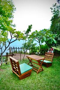 two wooden chairs and a picnic table in the grass at Asteya boutique stays in Varkala