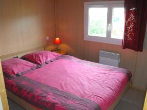 a bedroom with a pink bed and a window at Les Chalets du Piou in Bussières