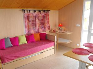 Habitación con cama con almohadas rosas y coloridas. en Les Chalets du Piou, en Bussières