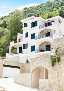 a white building with a stone wall at Apartments Boka Vista in Kamenari