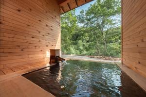 una piscina in un edificio di legno con acqua al suo interno di 孫六温泉六庵 a Senboku