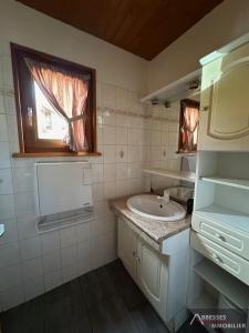 a white bathroom with a sink and a window at Chalet Les Jonquilles in Gérardmer
