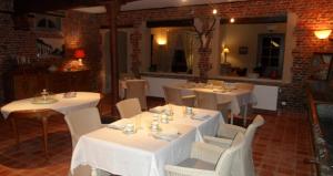 uma sala de jantar com mesas brancas e cadeiras brancas em Onsemhoeve em Dilbeek