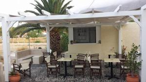 a group of tables and chairs under a white umbrella at Studio Mary in Perissa