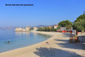 a beach with people swimming in the water at Apartments Kastilac near the beach in Kaštela