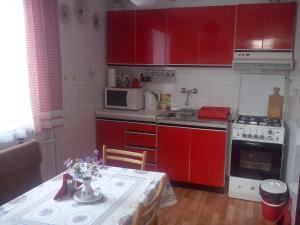 eine kleine Küche mit roten Schränken und einem Tisch mit einem Siddx-Tisch in der Unterkunft Retro Cottage Osturna in Osturňa
