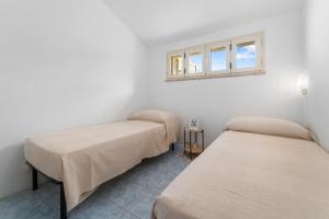 two beds in a room with a window at Domu Istella in SantʼAnna Arresi