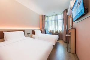 a hotel room with two beds and a flat screen tv at Hanting Hotel Beijing Jiaotong University Zoo in Beijing