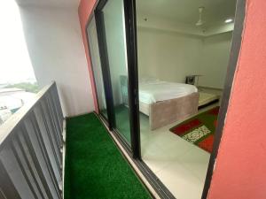 a room with a bed and a balcony with green carpet at LF Homestay I-city Studio, Shah Alam in Shah Alam