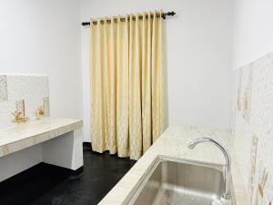 a bathroom with a sink and a shower curtain at Sigiri Bloom Villa in Sigiriya +34 photos
