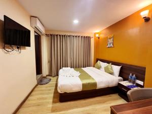 a hotel room with a bed and a television at Holiday Hostel Kathmandu in Kathmandu