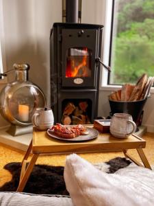 a table with a plate of food in front of a fireplace at Adventurer's Chest - Pohutukawa in Hotwater Beach