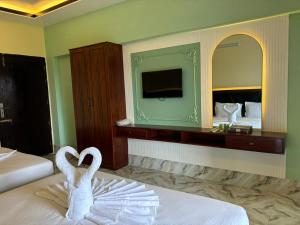 two swans are sitting on a bed in a hotel room at The Vacation Inn Hotel & Resort in Bāndarban