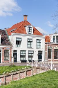 a white house with a fence in front of it at Appartement De Koesfabriek centrum Dokkum in Dokkum