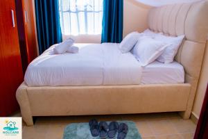 a bedroom with a bed with a pair of shoes on the floor at Nolcare Cozy haven-Kisumu in Kisumu