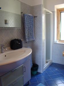 bagno piastrellato blu con lavandino e doccia di Casa Guerrino a Chiessi