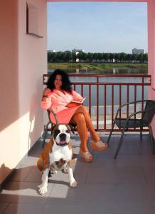 una mujer sentada en una silla con un perro en un balcón en Pension Oderblick, en Frankfurt de Oder