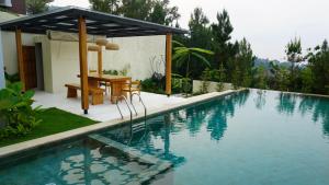 a swimming pool with a table next to a house at Villa Anvaya in Pasuruan