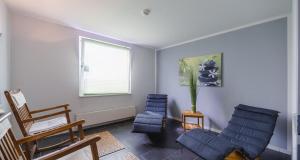 a living room with two blue chairs and a window at PLAZA INN Zwickau in Zwickau