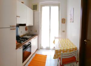 una cucina con armadi bianchi, tavolo e piano cottura di Casa Anna & Bruna a Marina di Ragusa