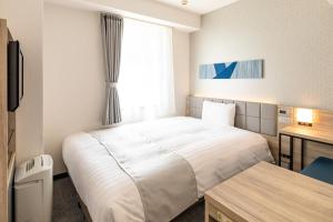 a hotel room with a bed and a desk and a window at Comfort Hotel Hiroshima Otemachi in Hiroshima