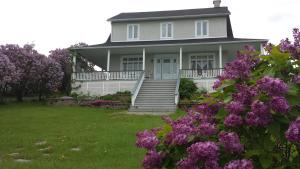 a white house with purple flowers in the yard at auberge gite maison des lilas in La Malbaie