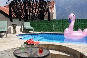 a pool with a pink inflatable swan in the middle at Sunny Days Villa in Prčanj