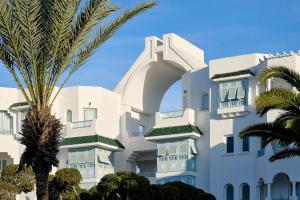 a white building with a palm tree in front of it at The Mirage Resort & SPA in Hammamet