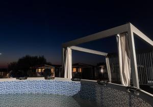 a patio with curtains and a pool at night at Szumi domek in Kołobrzeg