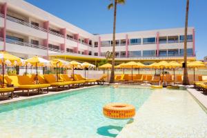 a swimming pool with chairs and umbrellas in front of a hotel at Los Felices Ibiza in San Antonio Bay