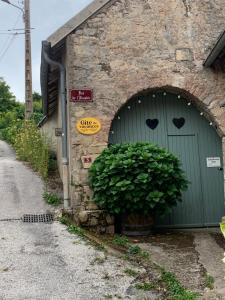 a green garage door with a plant in front of it at Appartement près de DOLE in Menotey