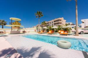 a swimming pool with chairs and umbrellas in a resort at Grand Paradiso Ibiza - Adults Only in San Antonio Bay