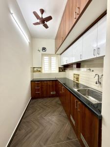 a kitchen with wooden cabinets and a ceiling fan at Q by Kolam - Women and Family Serviced Apartments, Thoraipakkam, OMR in Chennai +22 photos