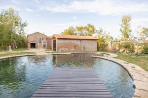 a pond with a wooden walkway in front of a house at Agriturismo Le Cerrete in Chiusi