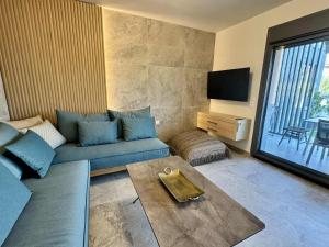 a living room with a blue couch and a television at Trinity Pool Villas GOLD in Iraklitsa