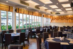 a dining room with tables and chairs and windows at Golden Empire Suvarnabhumi Hotel in Bang Kew Yai