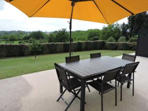 einen schwarzen Tisch und Stühle mit einem Sonnenschirm in der Unterkunft Gite du chêne vert - Périgord in Salignac Eyvigues