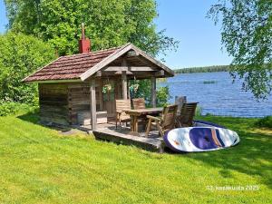 a small cabin with a table and a boat in the grass at Huvila Lahdenranta in Räyrinki