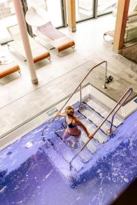 a woman in a swimming pool with a hand rail at Hotel Glemmtalerhof in Saalbach Hinterglemm