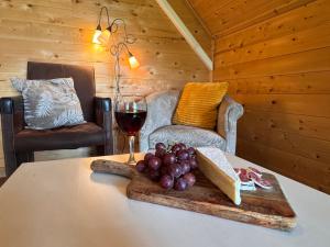 a table with a glass of wine and grapes on it at De Schutkooi - Tiny Houses in Vortum-Mullem