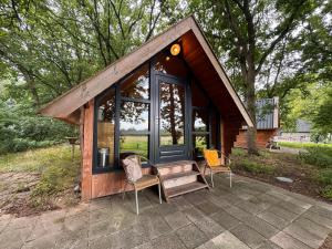 a tiny house with a porch and two chairs at De Schutkooi - Tiny Houses in Vortum-Mullem