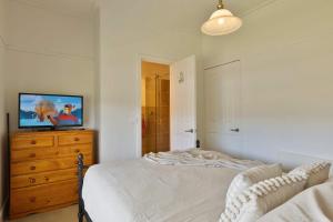 une chambre avec un lit et une télévision sur une commode dans l'établissement Cosy Candlewick Cottage - A Mount Beauty Delight, à Mount Beauty