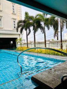 una piscina con palmeras en un edificio en Modern-esque Room at Megaworld, en Iloilo City